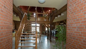 A spacious interior with a wooden staircase, brick walls, and a high ceiling. - Ostsee-Landhaus (Bastorf)