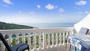 Un balcon avec vue sur la mer, une table recouverte d’une nappe et une chaise.