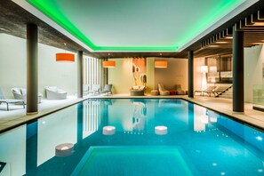 A modern indoor swimming pool with lounge chairs and a staircase. - Foerstlerhof (Postal)