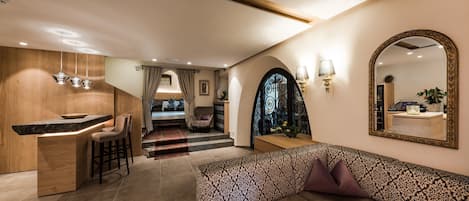 Un interior moderno con área de cocina, zona de estar con sofá estampado y un espejo grande en la pared.