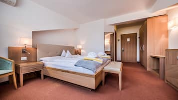 Una camera d'albergo con un letto in legno, comodini, una panca, una scrivania e un armadio.