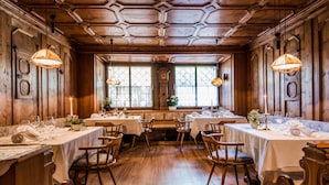 A dining area with wooden walls, hexagonal ceiling, and tables set for dining. - Foerstlerhof (Postal)