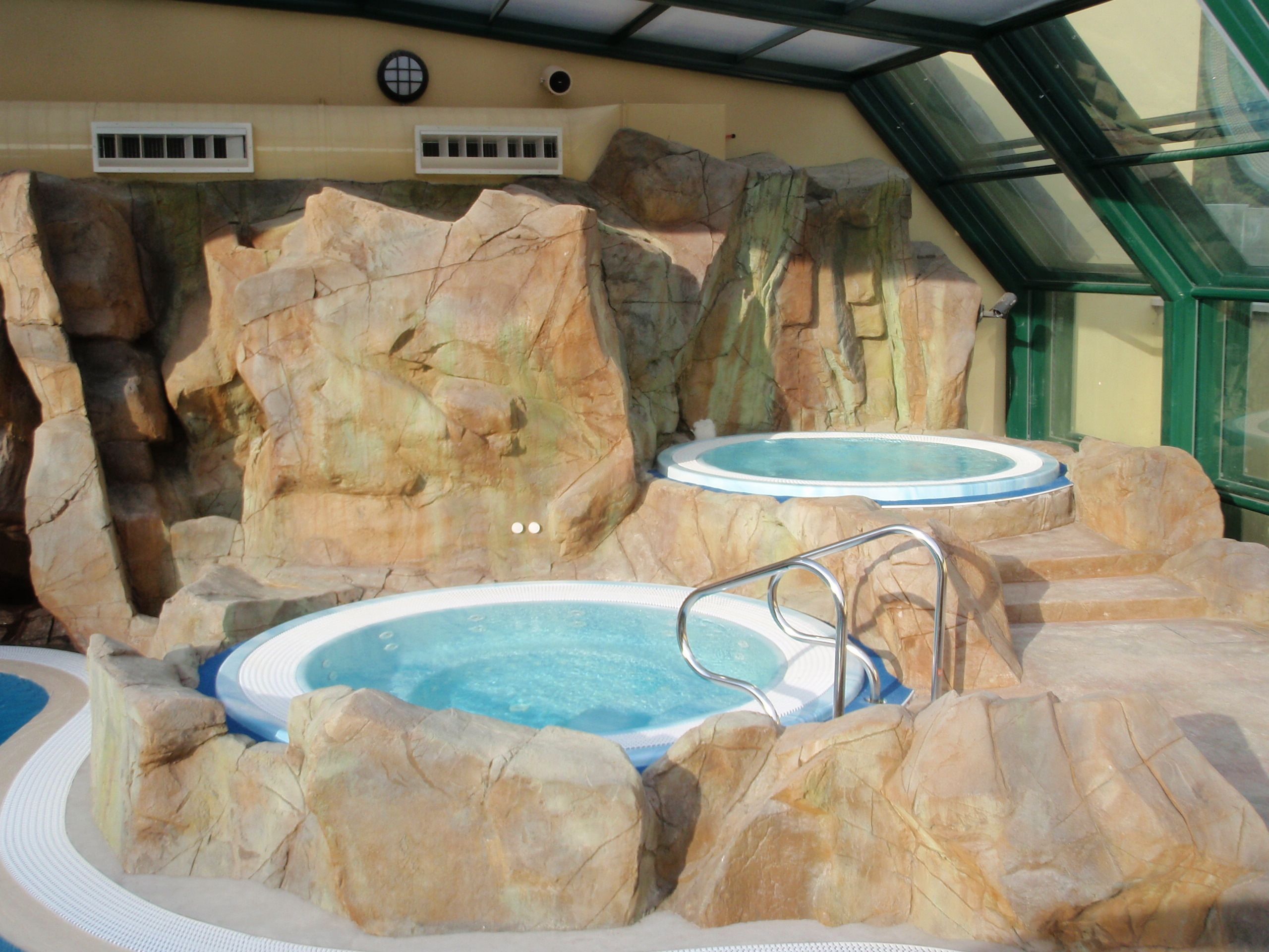 An indoor hot tub area with two hot tubs surrounded by rock formations.