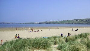 A beach with people, grass, and houses in the background. - Cardigan Bay Holiday Park (Cardigan)