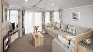A modern living room with a sofa, a coffee table, and a TV. - Cardigan Bay Holiday Park (Cardigan)