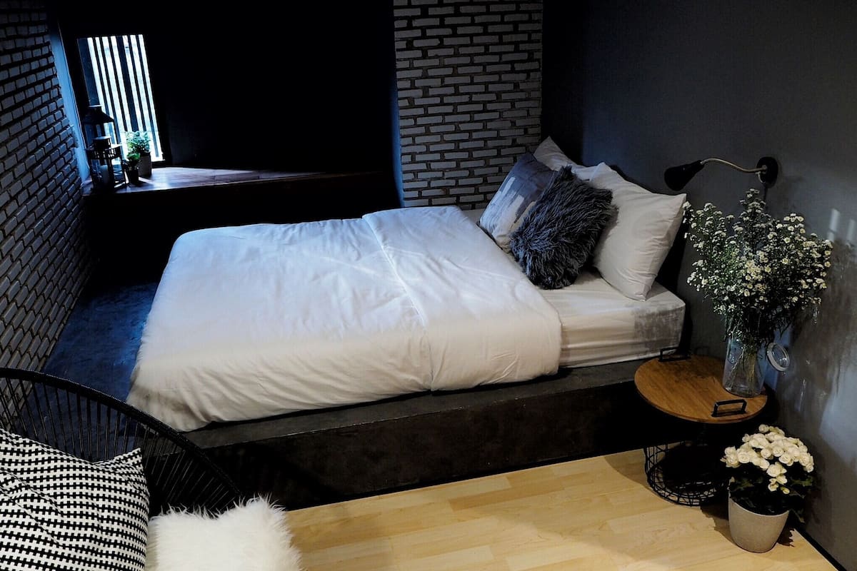 Un dormitorio moderno con cama, mesita de noche, silla y planta en maceta.