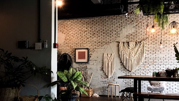 Ein gemütliches Interieur mit Backsteinwand, Wandbehängen aus Makramee und Holzmöbeln.