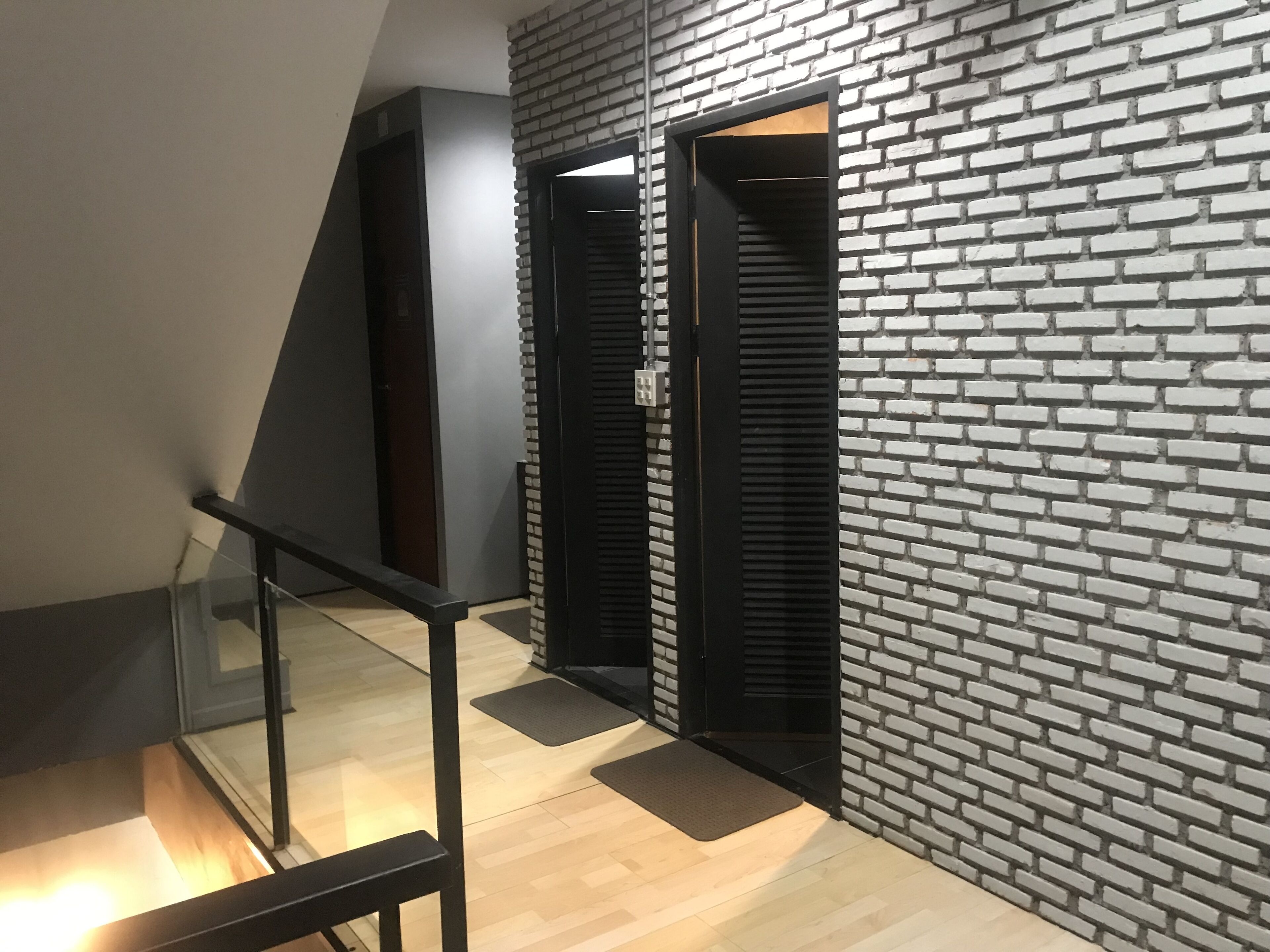 A modern interior with a brick wall, a wooden floor, and a black door.