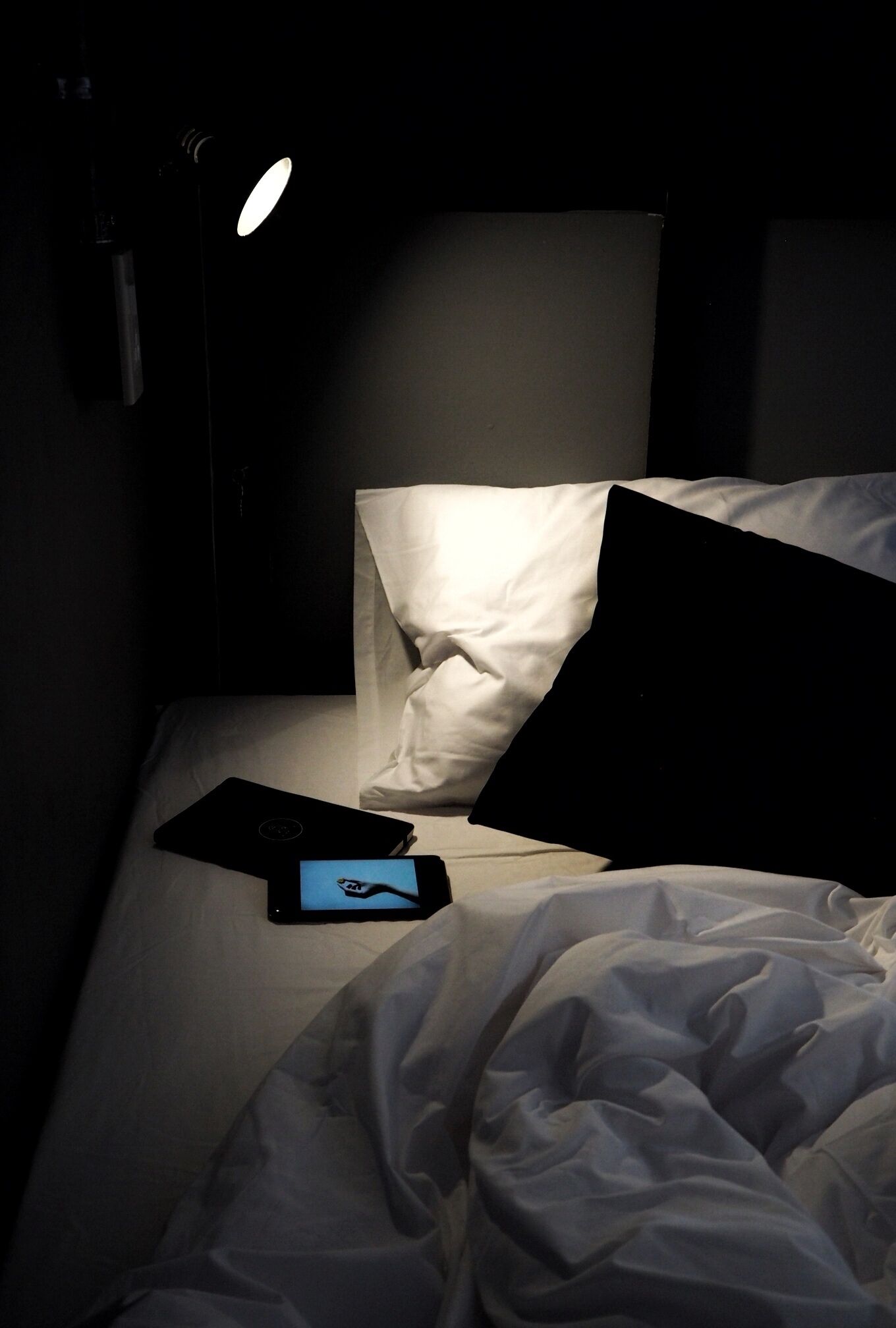 A dimly lit room with a bed, a laptop, and a smartphone on the bed.