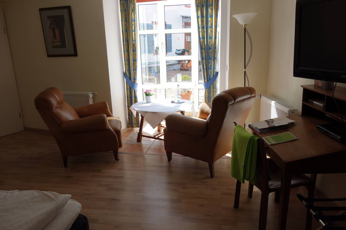 A living room with two leather armchairs, a wooden table, a television, and a window with curtains.