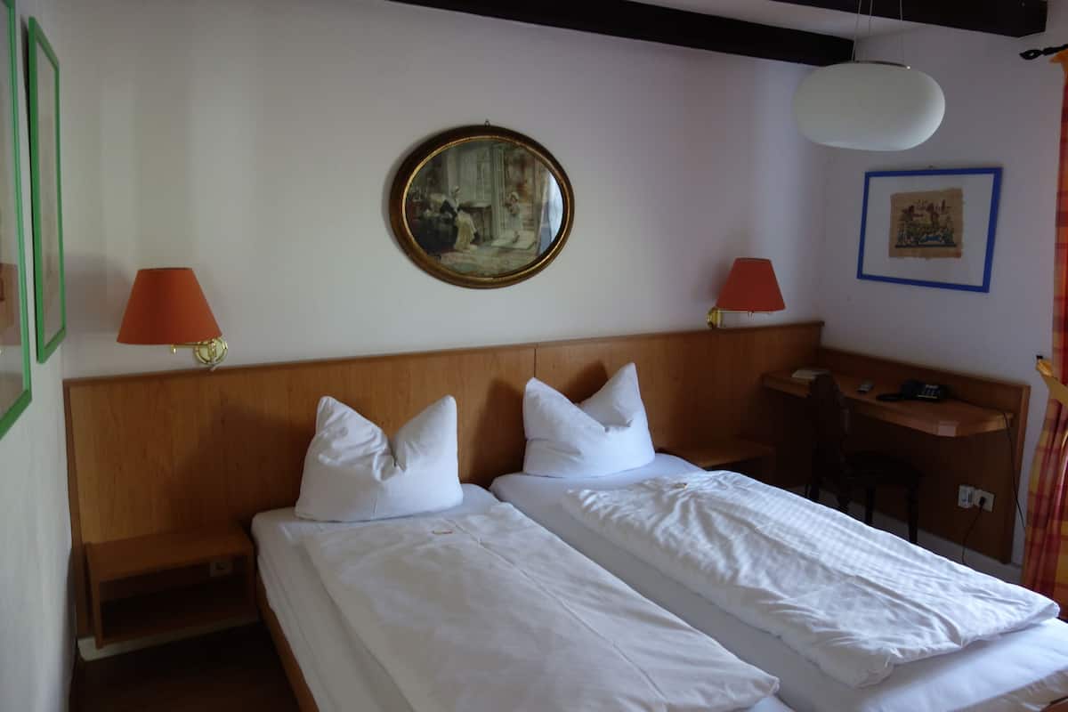 A double bed with white linens, a wooden headboard, two bedside tables with lamps, and a wall-mounted mirror.