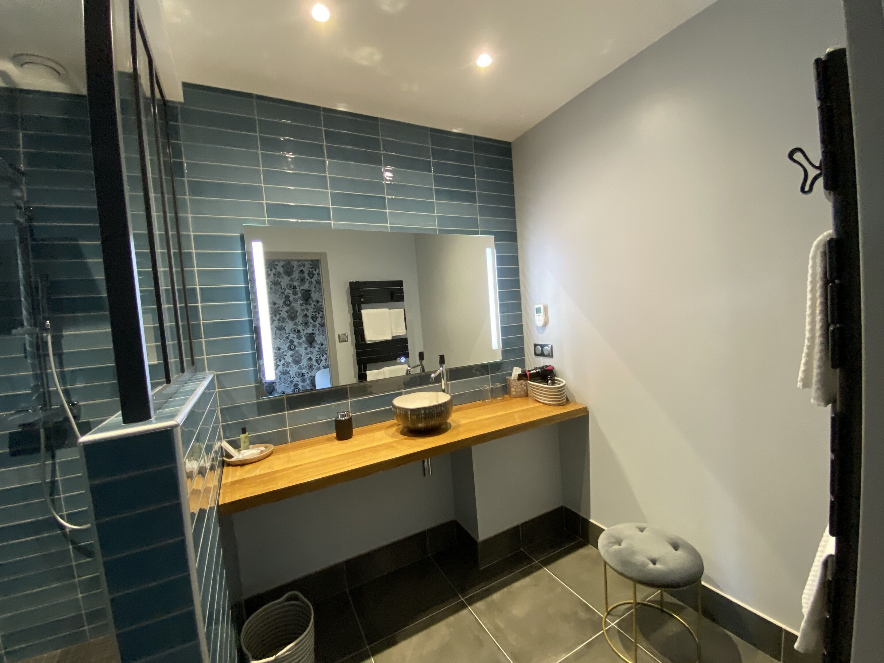 A modern bathroom with a large mirror, a wooden vanity, a sink, and a toilet.