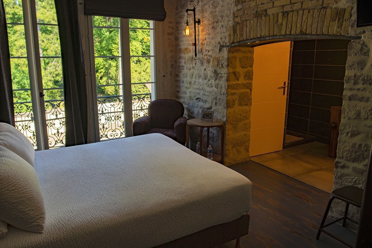 Un dormitorio con una cama grande, una silla, una mesita y vistas al exterior a través de una ventana.