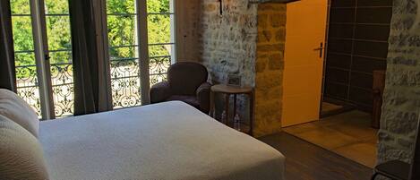 Un dormitorio con una cama grande, una silla, una mesita y vistas al exterior a través de una ventana.