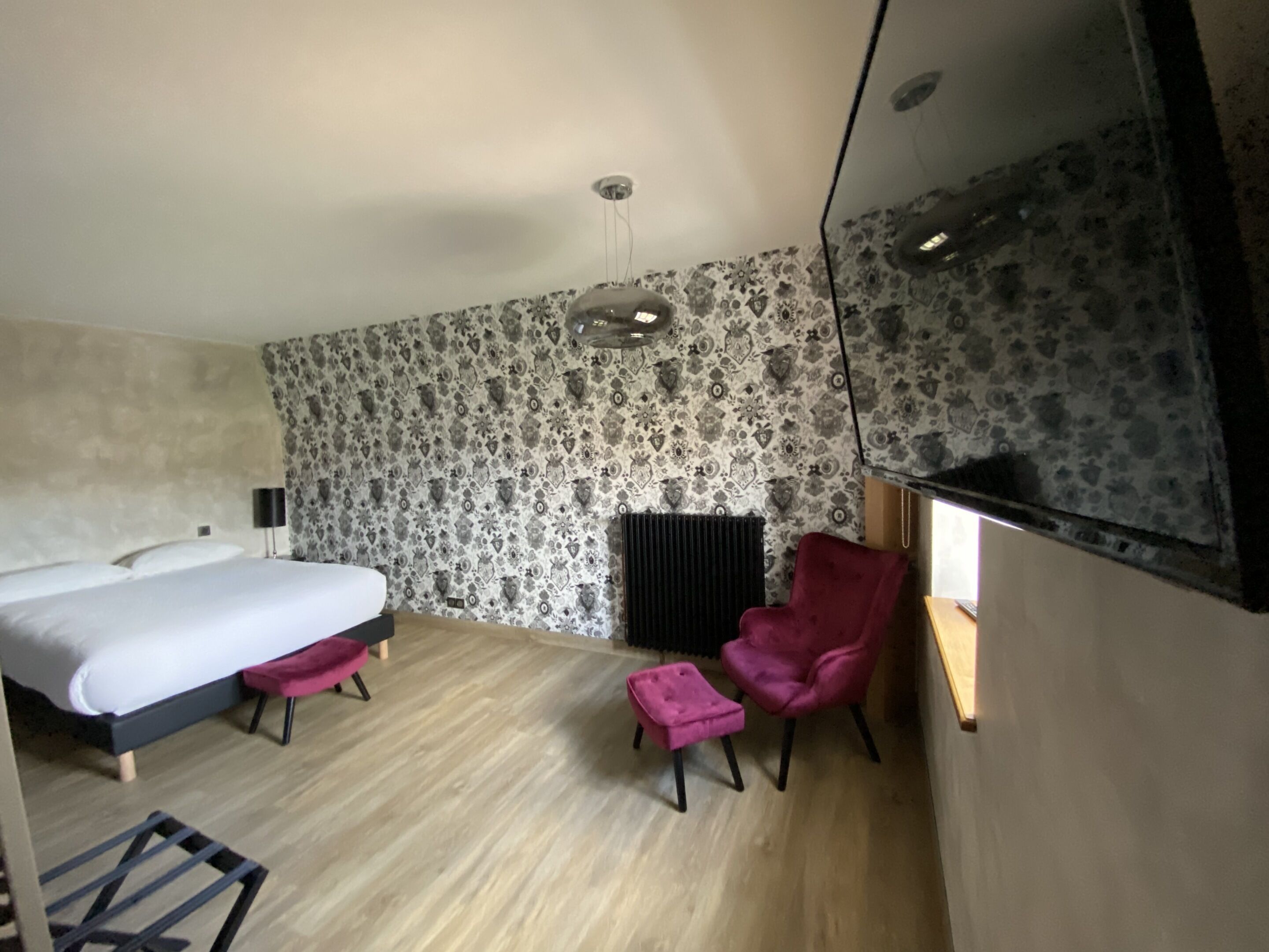 Ein Hotelzimmer mit Bett, Stuhl, kleinem Tisch und Heizkörper.