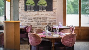 A restaurant with stone walls, wooden tables, and cushioned chairs. - Le Terminus (Tournus)