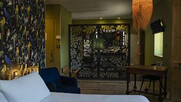 A bedroom with a bed, a desk, a chair, and a decorative wall.