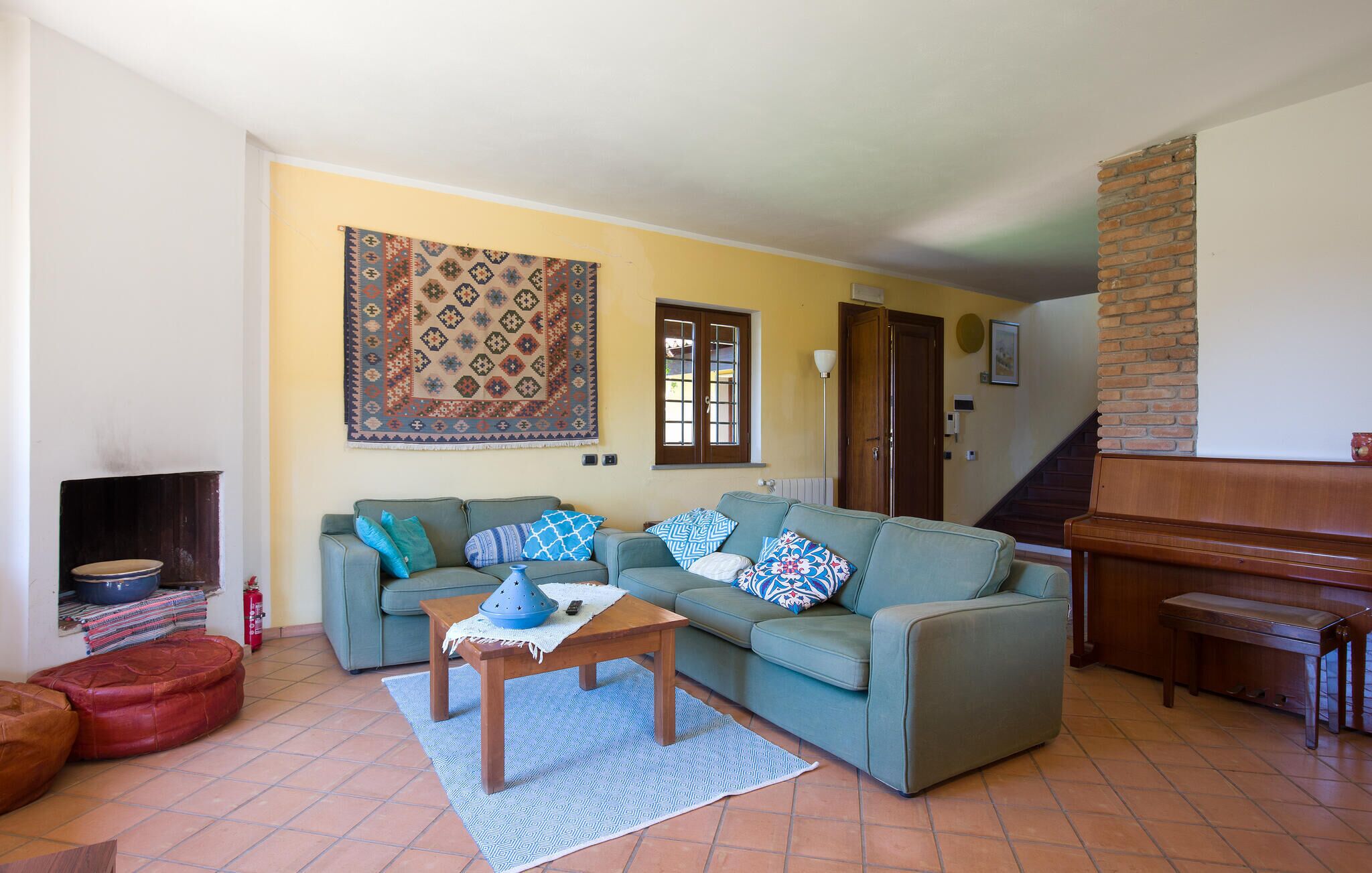 A living room with a sofa, a coffee table, a patterned rug, a fireplace, and a staircase.
