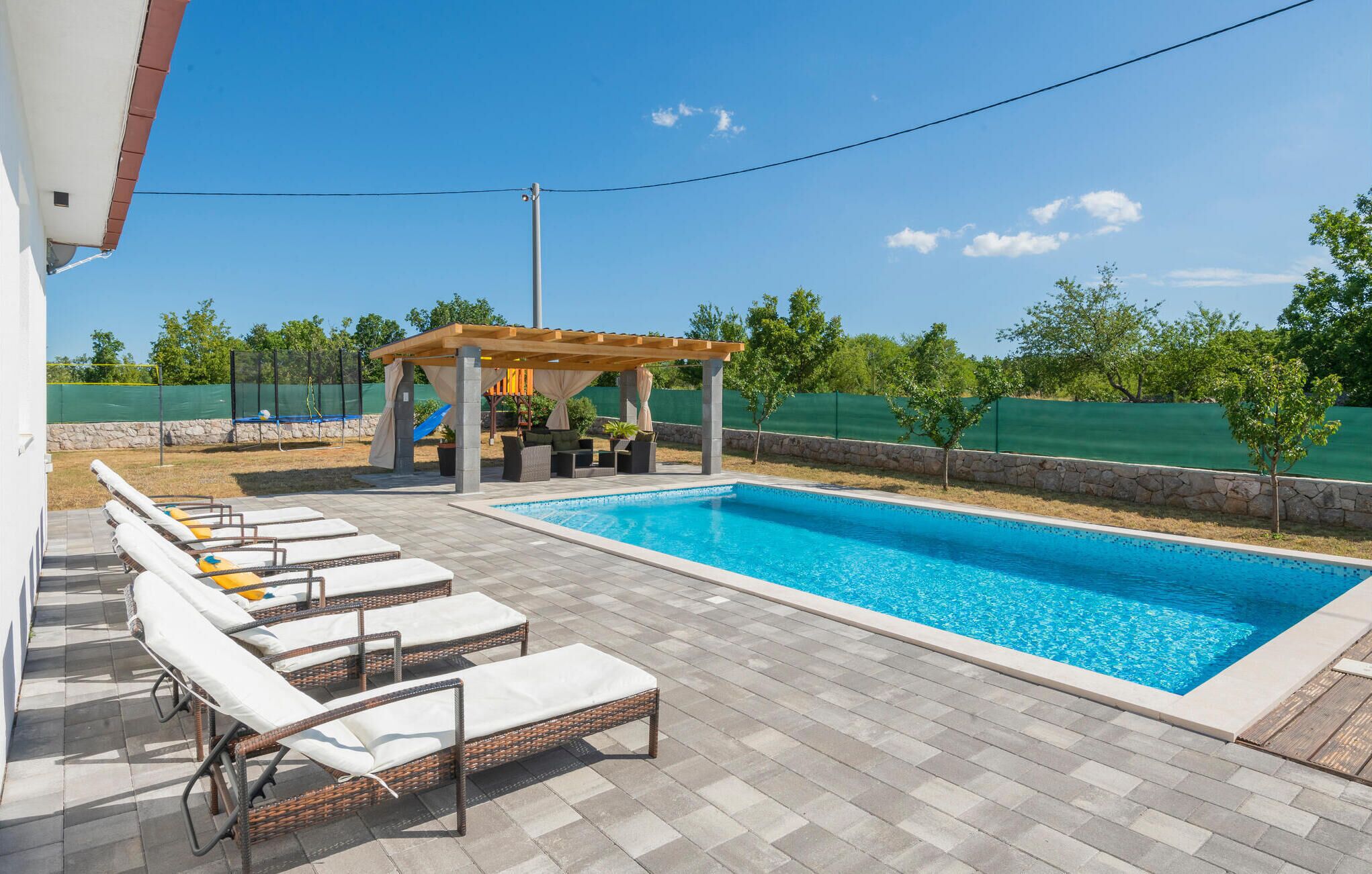 Una piscina amb gandules i una pèrgola.