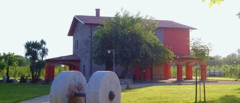 A building with a red and grey facade, two large cylindrical structures in the foreground, and a well-maintained lawn.
