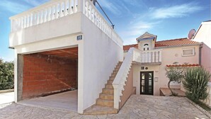 Un edificio con facciata bianca, un portone garage in mattoni e una scalinata che conduce a una porta con il numero 110.