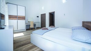 Un dormitori modern amb un llit gran, un escriptori, una cadira i un armari.