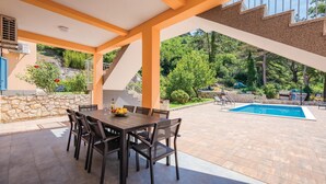 Terrassa exterior amb taula i cadires, una piscina i un mur de pedra.