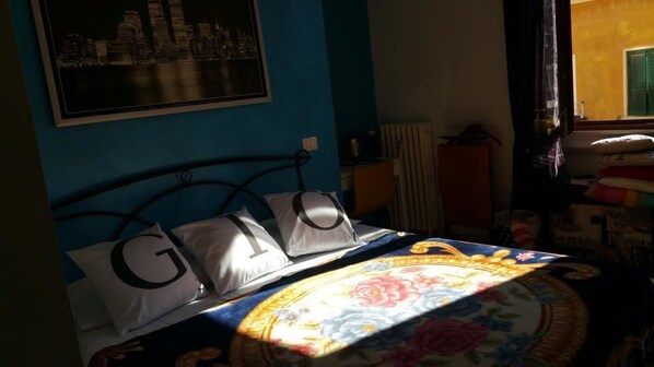 A bedroom with a bed, pillows with letters, a window, and a radiator. - A Casa Di Giò (Rome)