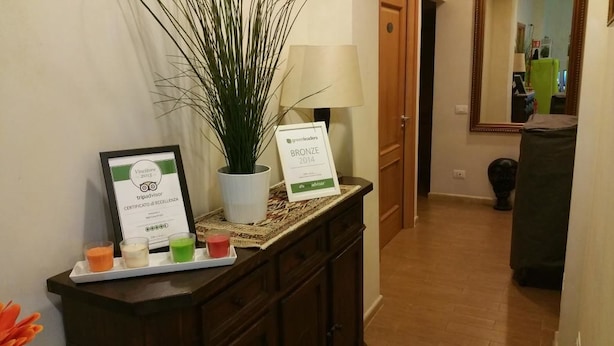 A reception area with a framed certificate, a potted plant, a tray with drinks, and a 'Bronze 2014' award sign. - A Casa Di Giò (Rome)