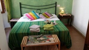 A room with a bed, a bedside table, a nightstand, a small wooden table with magazines, and a lamp. - A Casa Di Giò (Rome)