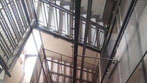 A spiral staircase with metal railings and a concrete wall. - A Casa Di Giò (Rome)