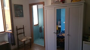 Una habitación con una silla de madera, un armario y una puerta que da a un baño.