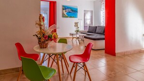 A modern living room with a sofa, a dining table with chairs, and a painting on the wall.