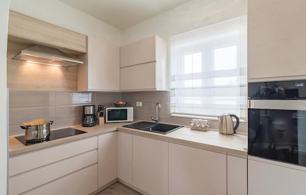 A modern kitchen with a microwave, coffee maker, kettle, and a stove. - Gorgeous home in Radeki Polje with sauna (Radeki Polje)