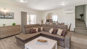 Un salon moderne avec un canapé d’angle, une table basse et une vue sur la cuisine.