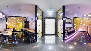 Un hall d’hôtel moderne, conçu selon un plan circulaire, comprenant un comptoir d’accueil, un espace salon et un couloir menant aux autres chambres.