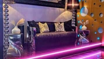 Ein modernes Wohnzimmer mit einem dunkelgrauen Sofa, einem großen Spiegel und einer Wand mit runden Aussparungen.