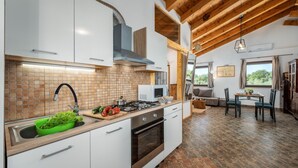 A modern kitchen with white cabinets, a wooden ceiling, and a dining area with a table and chairs. - Lovely home in Pula with WiFi (Pula)