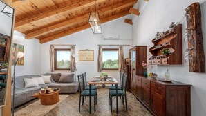 A cozy room with a wooden ceiling, a dining table with chairs, a sofa, and a cabinet with jars. - Lovely home in Pula with WiFi (Pula)