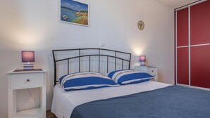 Une chambre à coucher avec un lit, deux tables de chevet avec des lampes, une armoire rouge et un tableau au mur.