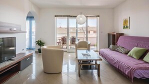 Un salon moderne avec un téléviseur à écran plat, un canapé, une table basse et une table à manger.