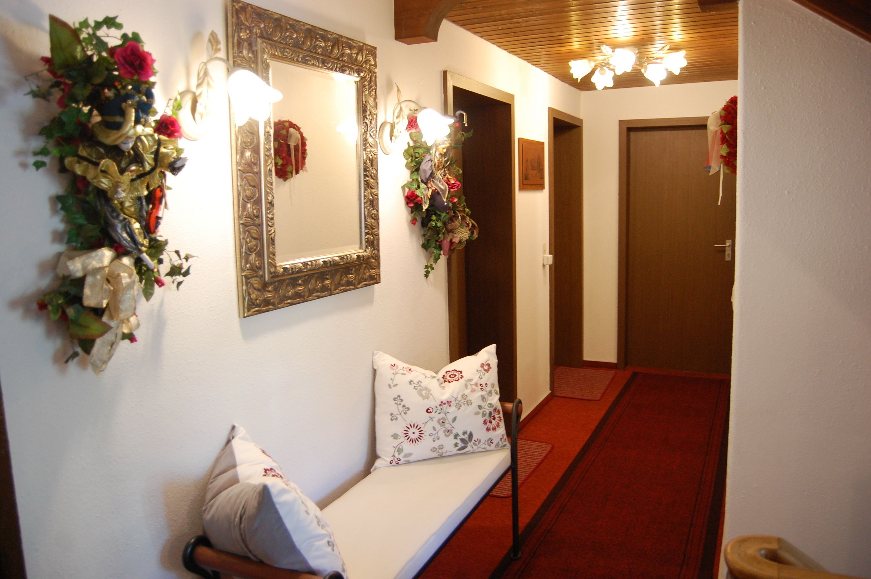Un couloir avec un banc, un miroir et des décorations florales.