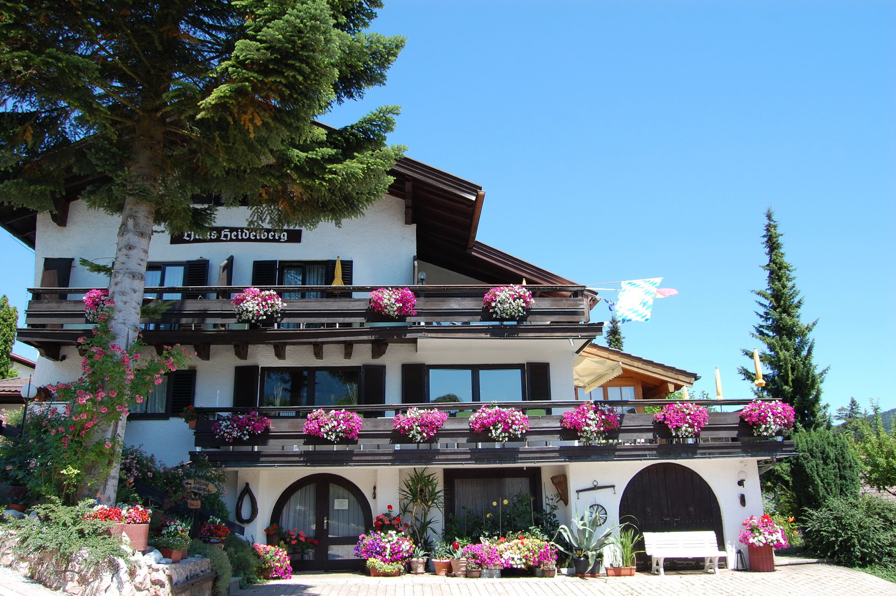 A hotel with a white facade, multiple balconies with flower boxes, and a sign reading "Hotel Heidberg".