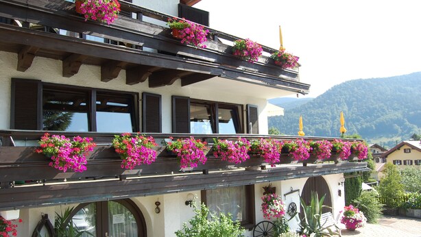 Edifício com várias varandas decoradas com floreiras suspensas.