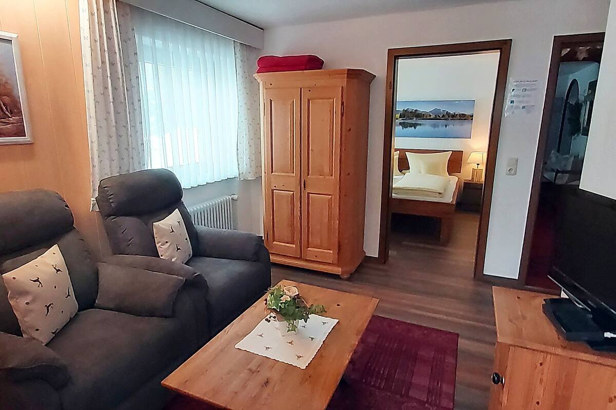 Un salon avec un canapé, un meuble en bois, une télévision et un tableau accroché au mur.