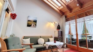 Uma sala de estar aconchegante com um sofá verde, uma mesa pequena e uma TV.