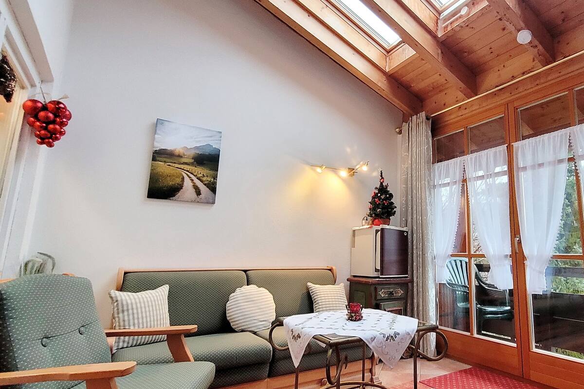 Un salon confortable avec un canapé vert, une petite table et un téléviseur.