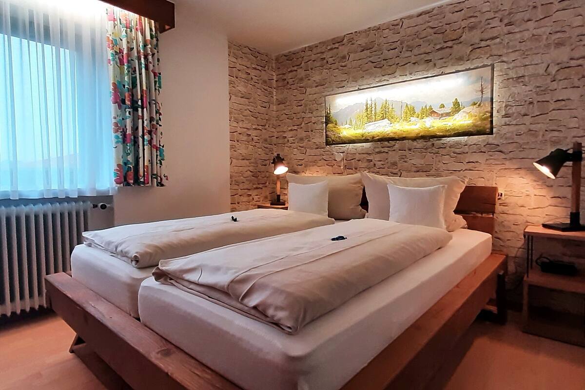 Une chambre à coucher avec un lit double, un mur en pierre, un tableau et une table de chevet avec une lampe.