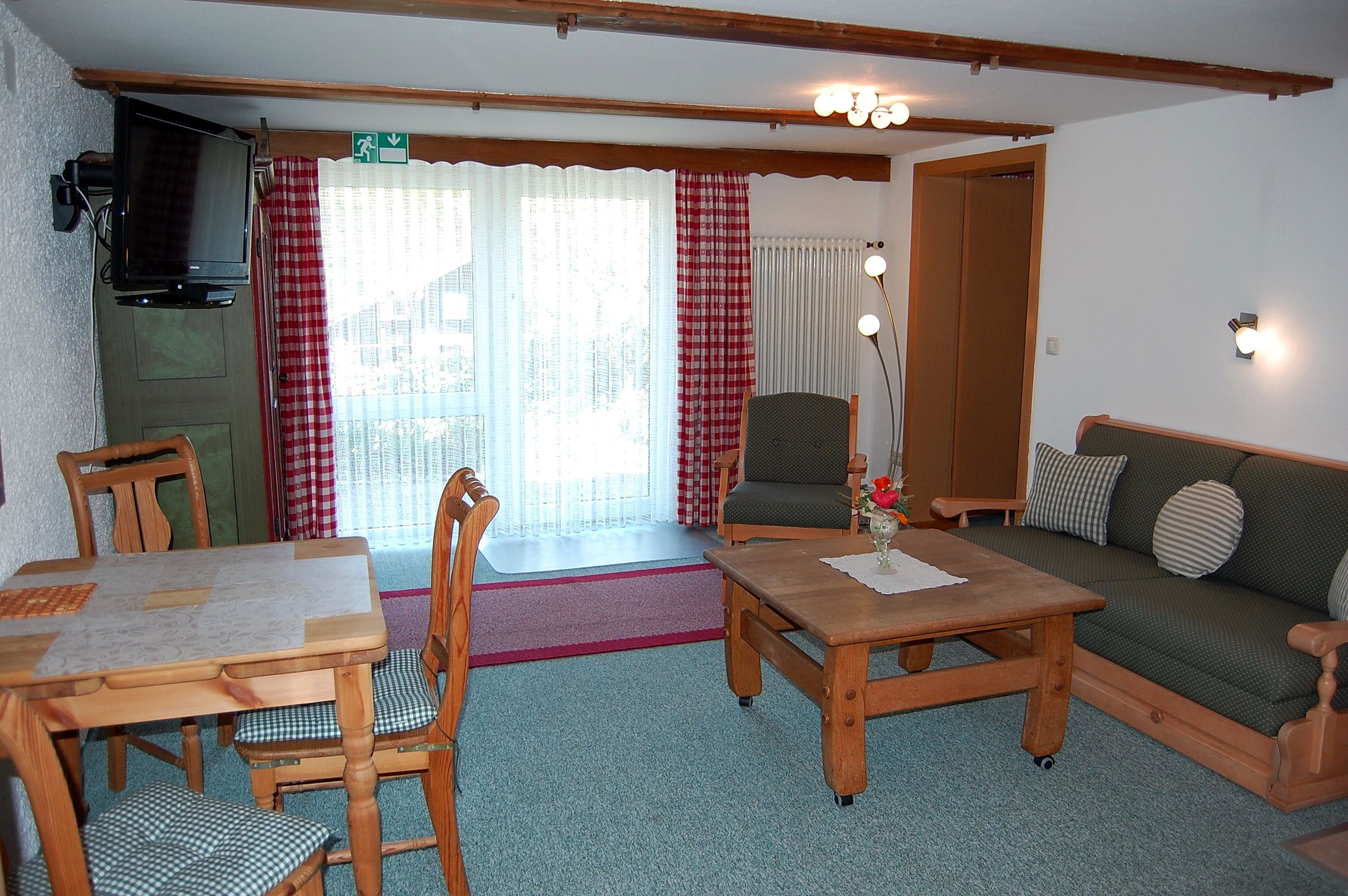 A cozy room with a wooden table, chairs, a sofa, and a television.
