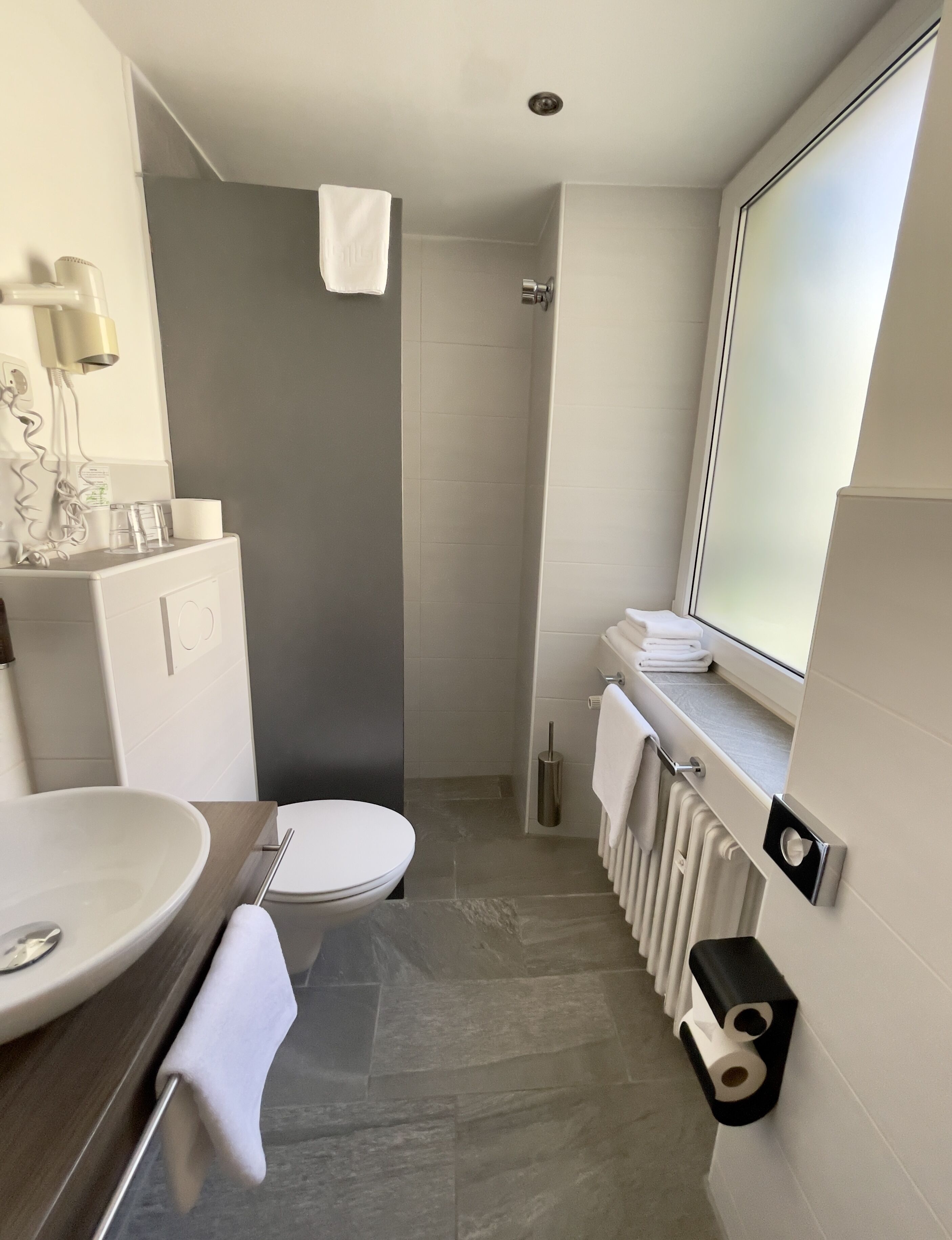 A modern bathroom with a toilet, sink, and shower.